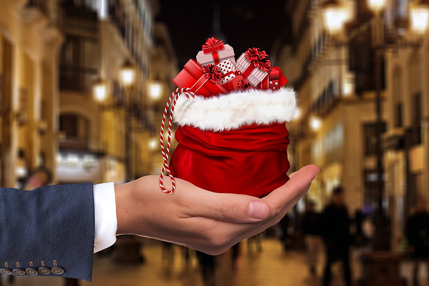 Hand holding Christmas gift sack on blurred city street