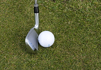 Silver Golf Wedge and White Ball on Green Grass