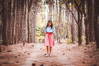 Young woman reading a book while walking in a forest