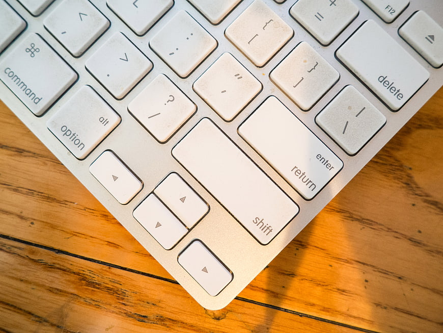 Close-up of white computer keyboard on wooden desk