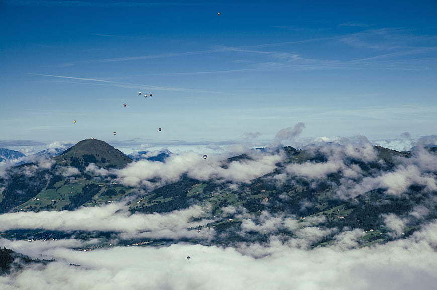 Paragliders soaring above misty mountain peaks and clouds