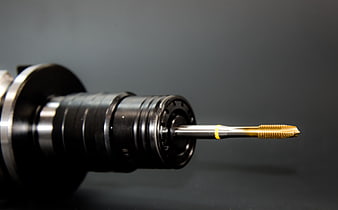 Close-up of CNC machine spindle with gold cutting tool