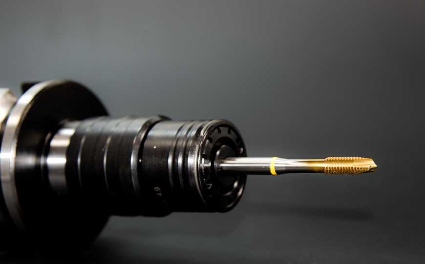 Close-up of CNC machine spindle with gold cutting tool