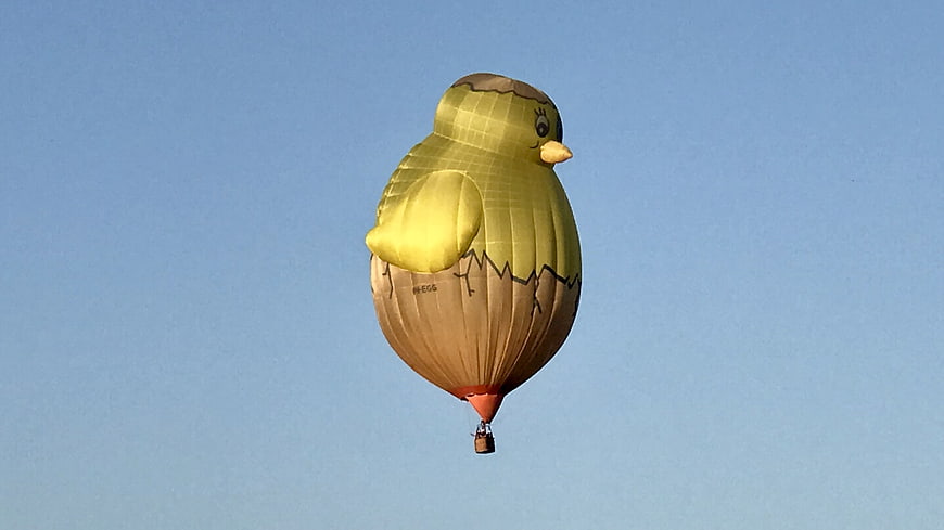 Yellow Chick Hot Air Balloon Flying in Blue Sky
