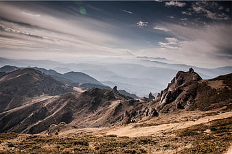 Dramatic Mountain Landscape with Rolling Hills and Cloudy Sky