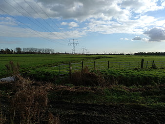 Green Pasture with High Voltage Power Lines and Cloudy Sky