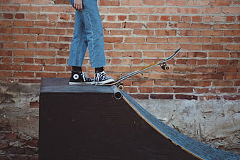 Skateboarder on ramp against brick wall