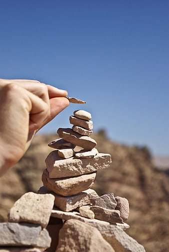 Hand Balancing Stones in Desert Landscape