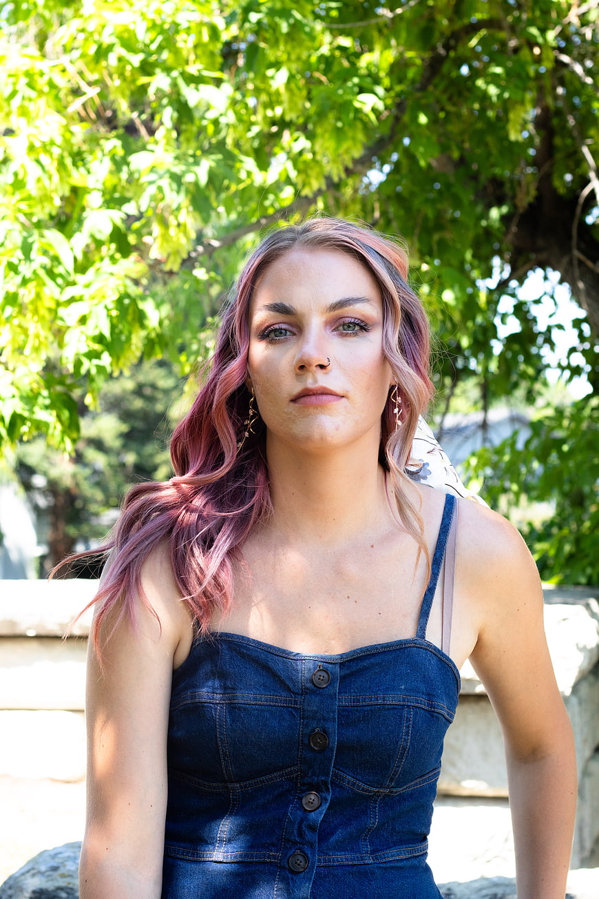 Portrait of young woman with pink hair in denim dress outdoors