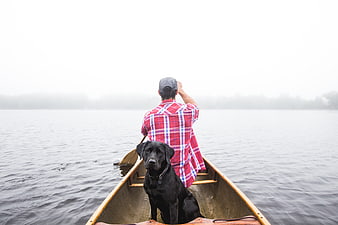 Man and Black Dog in Canoe on Foggy Lake