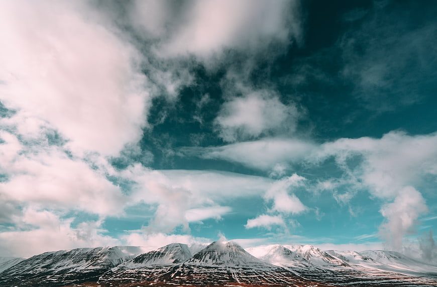 Dramatic Snow-Capped Mountains Under Teal Cloudy Sky
