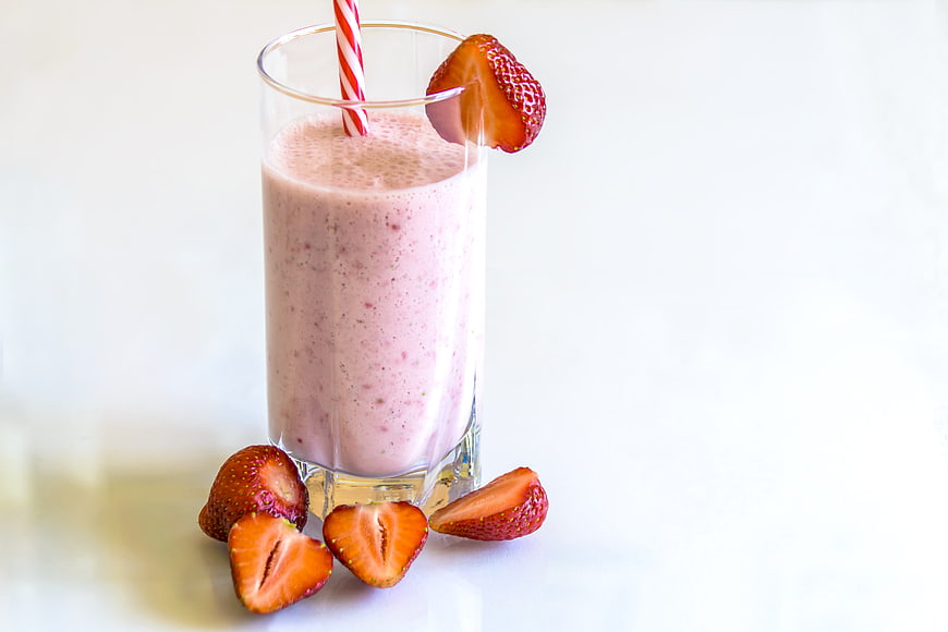Fresh Strawberry Smoothie in Glass with Straw and Fruit