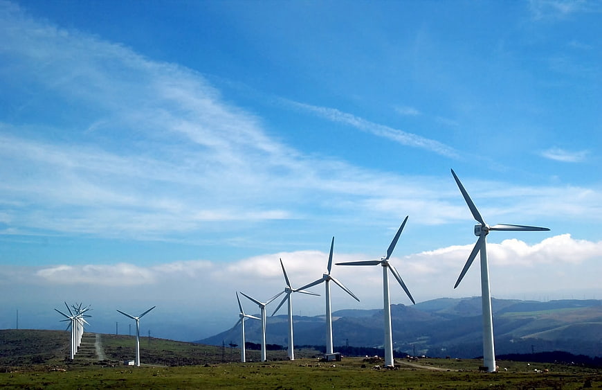 Wind Turbines on Green Hillside Under Blue Sky