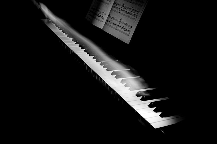 Motion blur of hands playing piano keys with sheet music