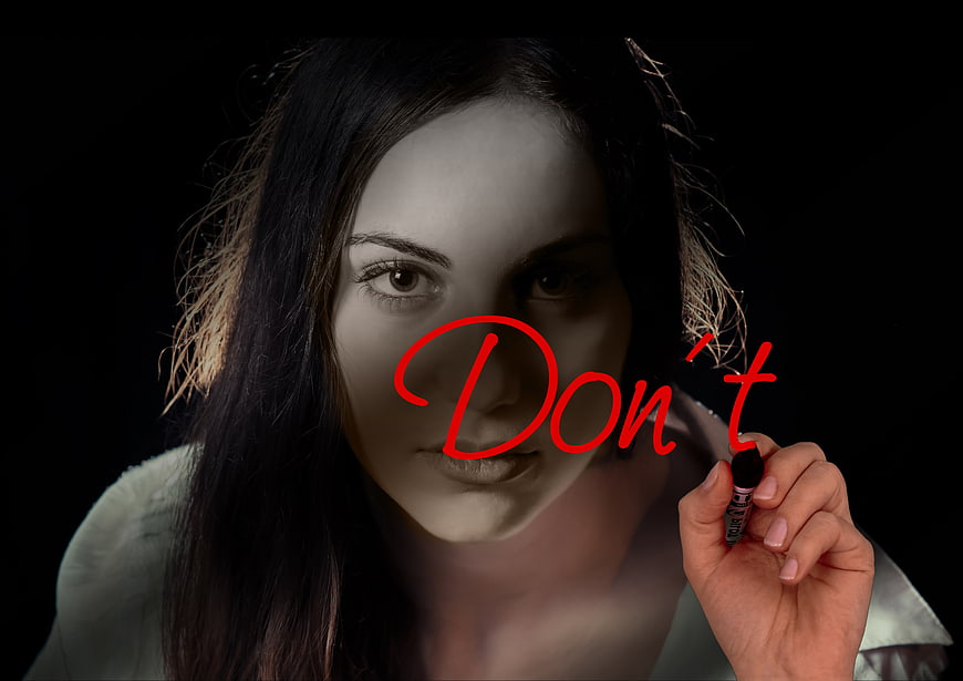 Woman writing Don't on glass with red marker
