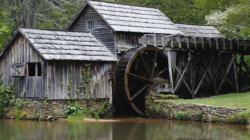 Historic wooden grist mill with large water wheel by river