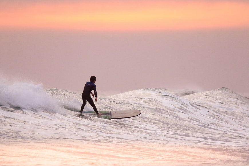 Surfer Riding Wave at Sunset Ocean