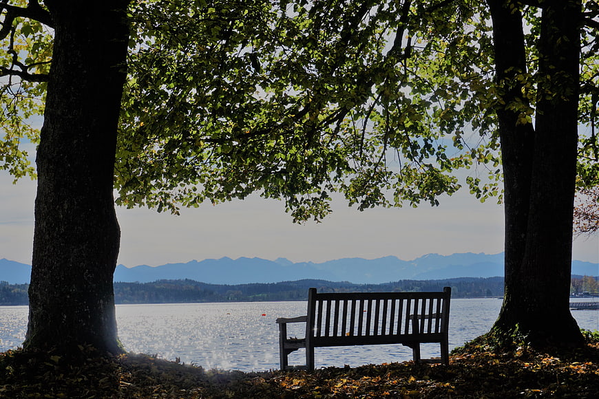 Wooden bench by lake with mountains and trees