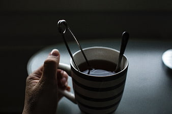 Hand holding striped coffee mug with tea infuser