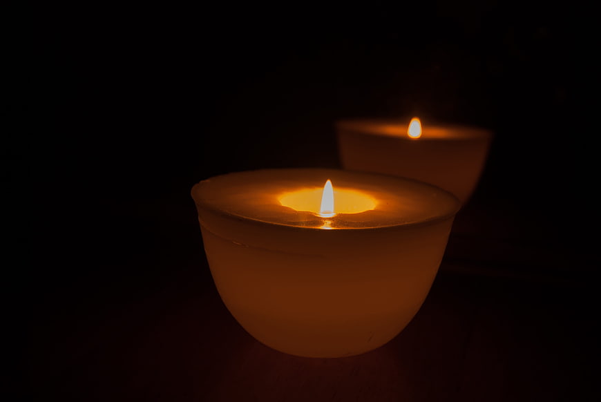 Two lit candles glowing in the dark