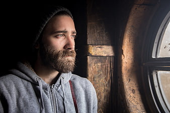 Bearded man in beanie looking out window