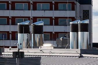 Stainless Steel Ventilation Ducts On Rooftop Against Red Building Facade