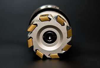 Close-up of CNC milling cutter with gold carbide inserts on dark background