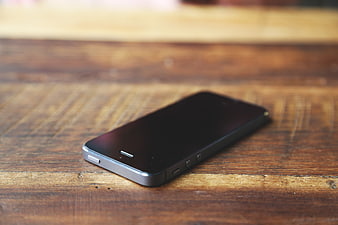 Black smartphone on rustic wooden table