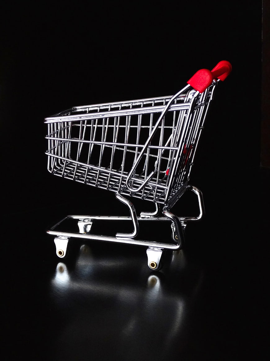 Miniature Shopping Cart with Red Handle on Black Background