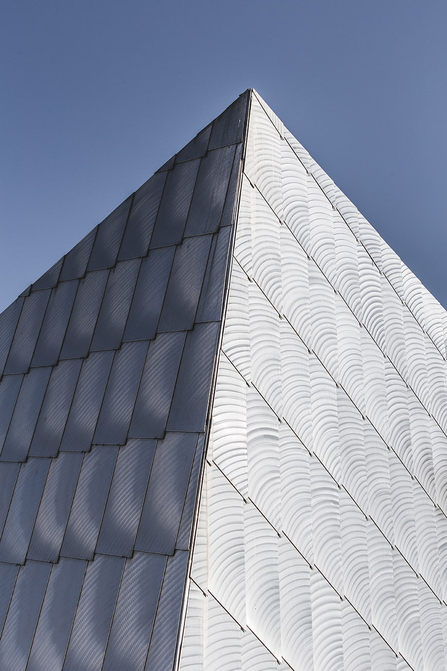 Modern Pyramid Building with Textured Facade Against Blue Sky