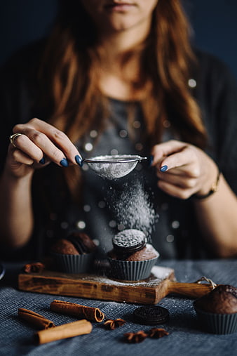Woman Sifting Powdered Sugar onto Chocolate Muffins
