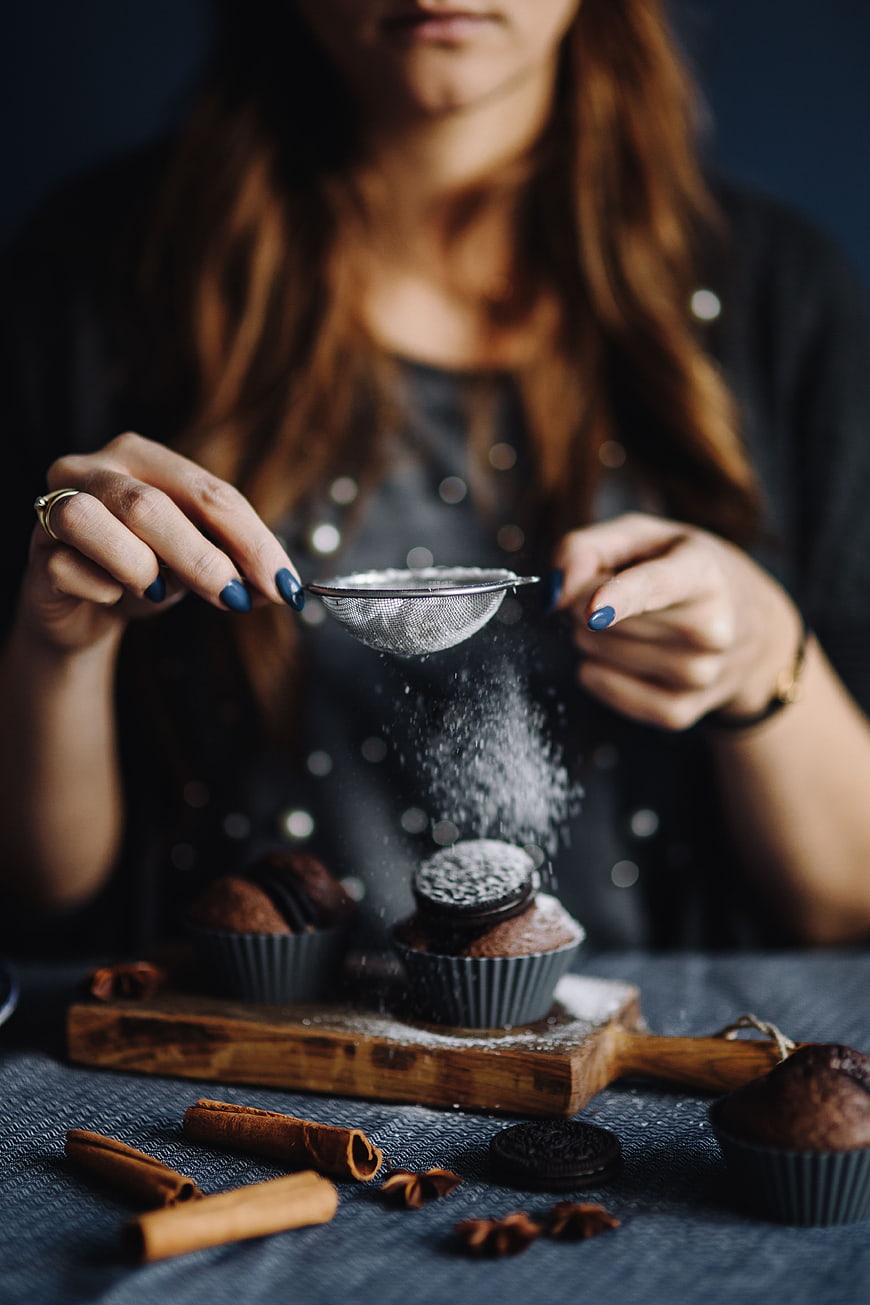 Woman Sifting Powdered Sugar onto Chocolate Muffins