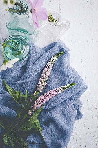 Flat lay of pink flowers and blue linen on white wood