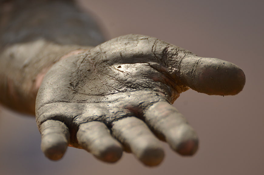 Close-up of a hand covered in dried mud reaching out