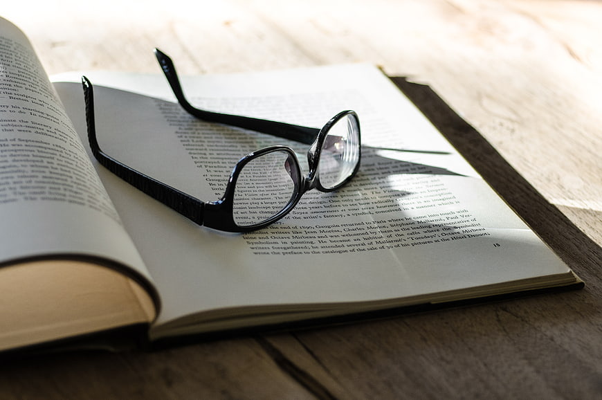Black Glasses Resting on Open Book Pages