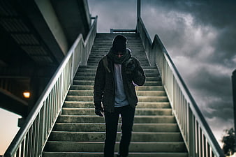 Man Walking Down Stairs Under Dramatic Cloudy Sky
