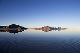 Serene desert lake reflecting mountains under clear blue sky