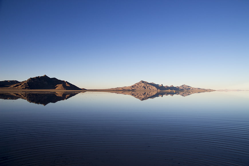 Serene desert lake reflecting mountains under clear blue sky