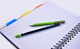 Green pen and pencil on graph paper notebook