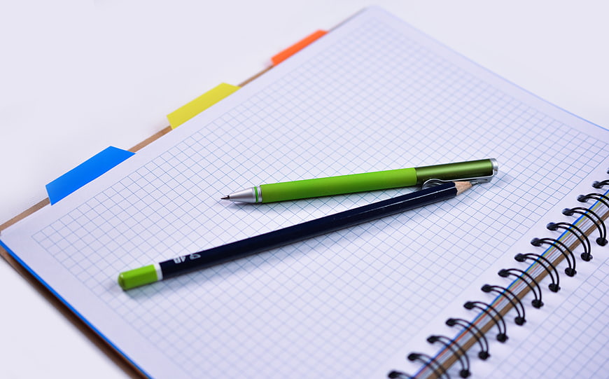 Green pen and pencil on graph paper notebook