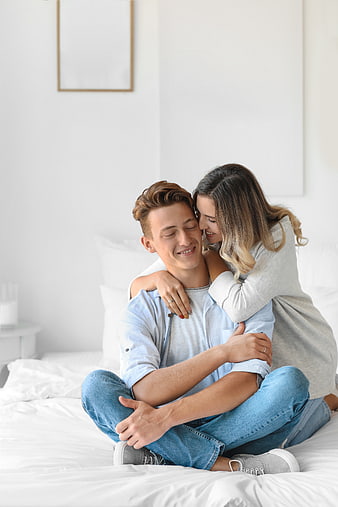 Happy couple hugging on bed in bright bedroom