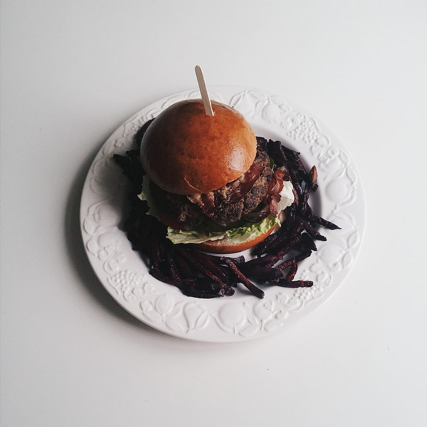 Top view gourmet burger with beetroot fries on white plate