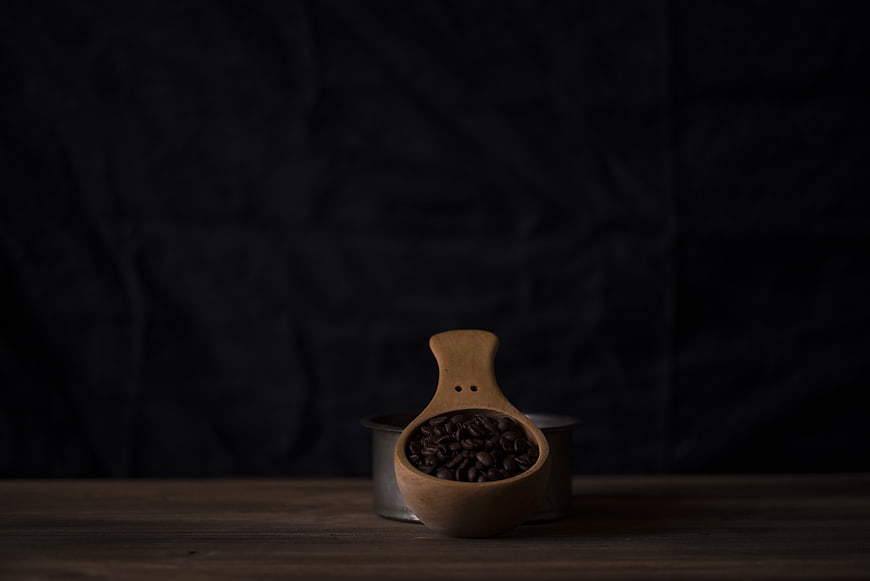 Wooden Scoop with Coffee Beans on Dark Background