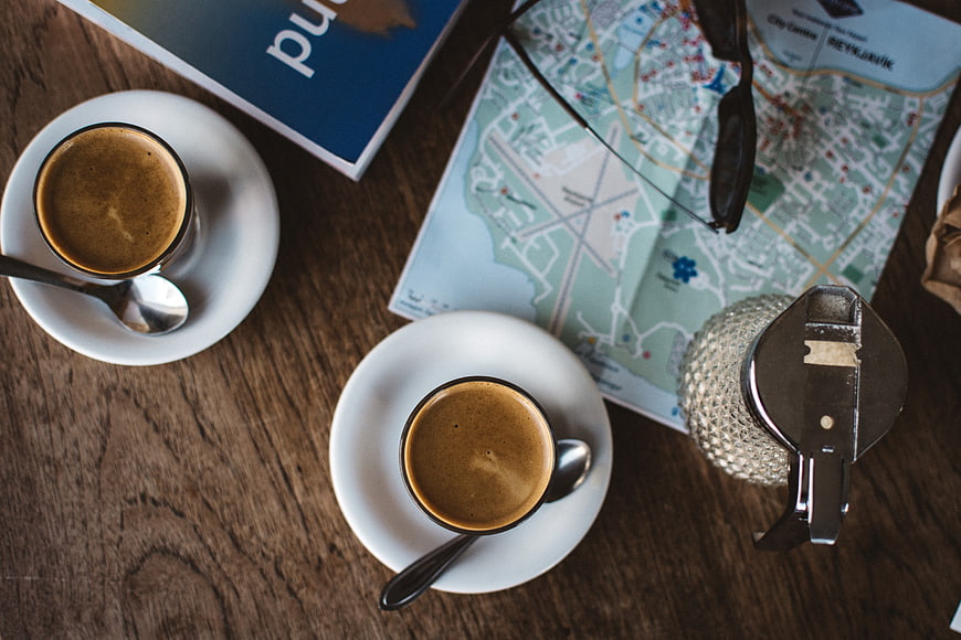 Top view of coffee, map, and camera on wooden table