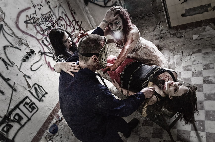 Horror scene with masked killer and bloody zombies in abandoned room