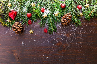 Christmas fir branches with ornaments and pinecones on dark wood