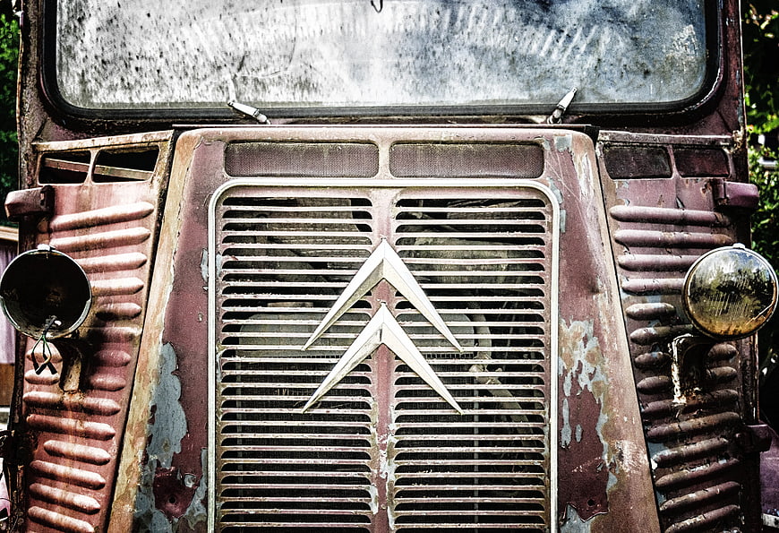 Rusty vintage car grille with emblem and headlights