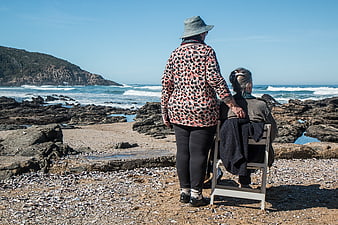 Senior women friends looking at ocean view from rocky beach
