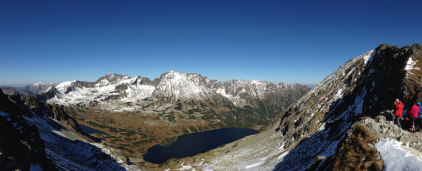 Panoramic view of snow-capped High Tatras mountains with alpine lake