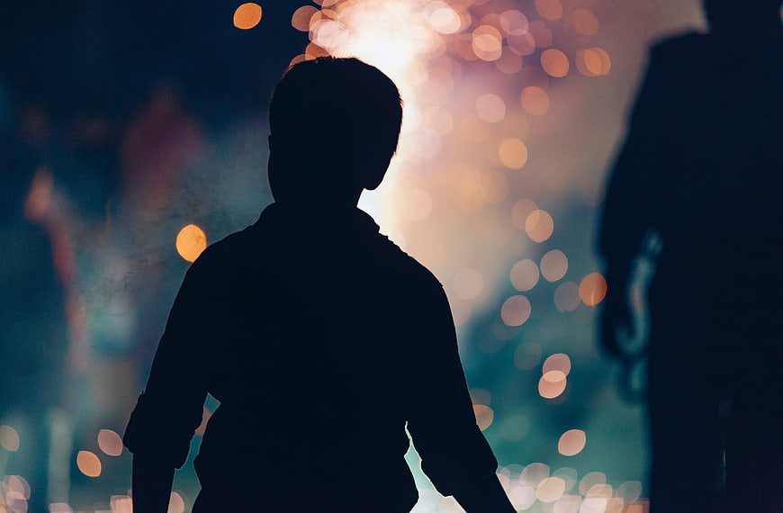 Silhouette of Boy Watching Fireworks at Night
